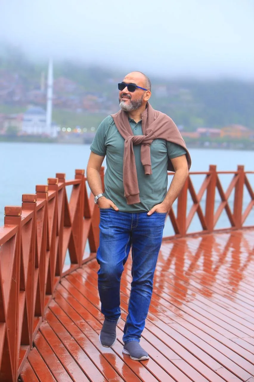 Dr. Abu-Sheikha walking along a wet red boardwalk beside a lake